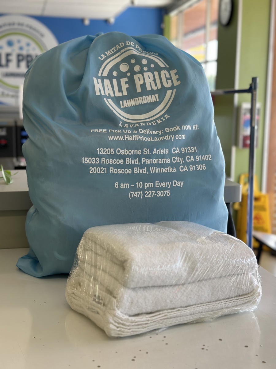 A branded Half Price Laundry bag beside a stack of neatly folded laundry