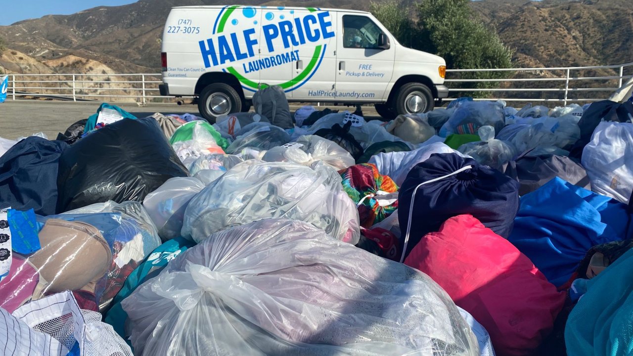 Half Price Laundry van behind a large intake of bagged clothing and soft goods